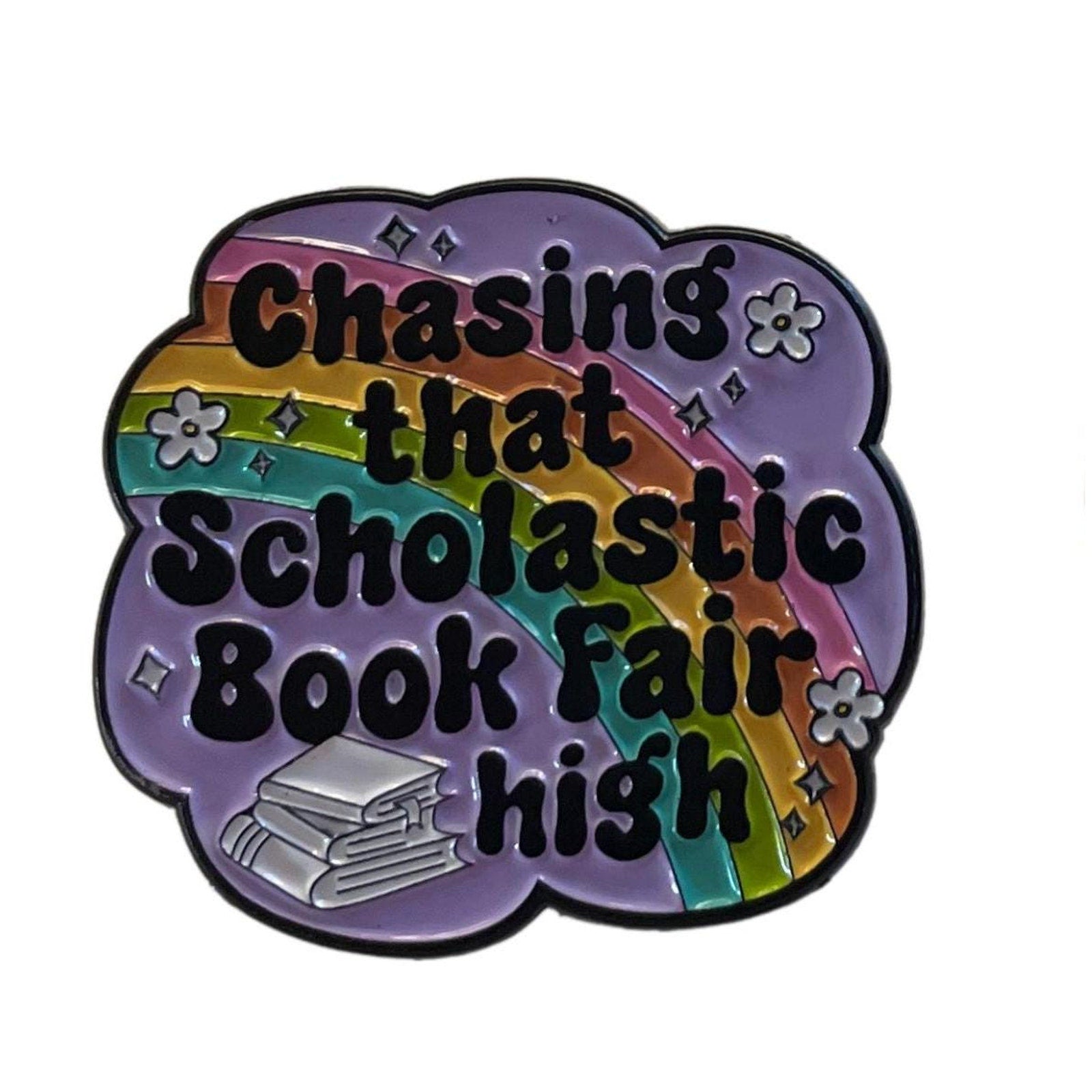 Chasing that Scholastic Book Fair high enamel pin with rainbow background and stack of books design